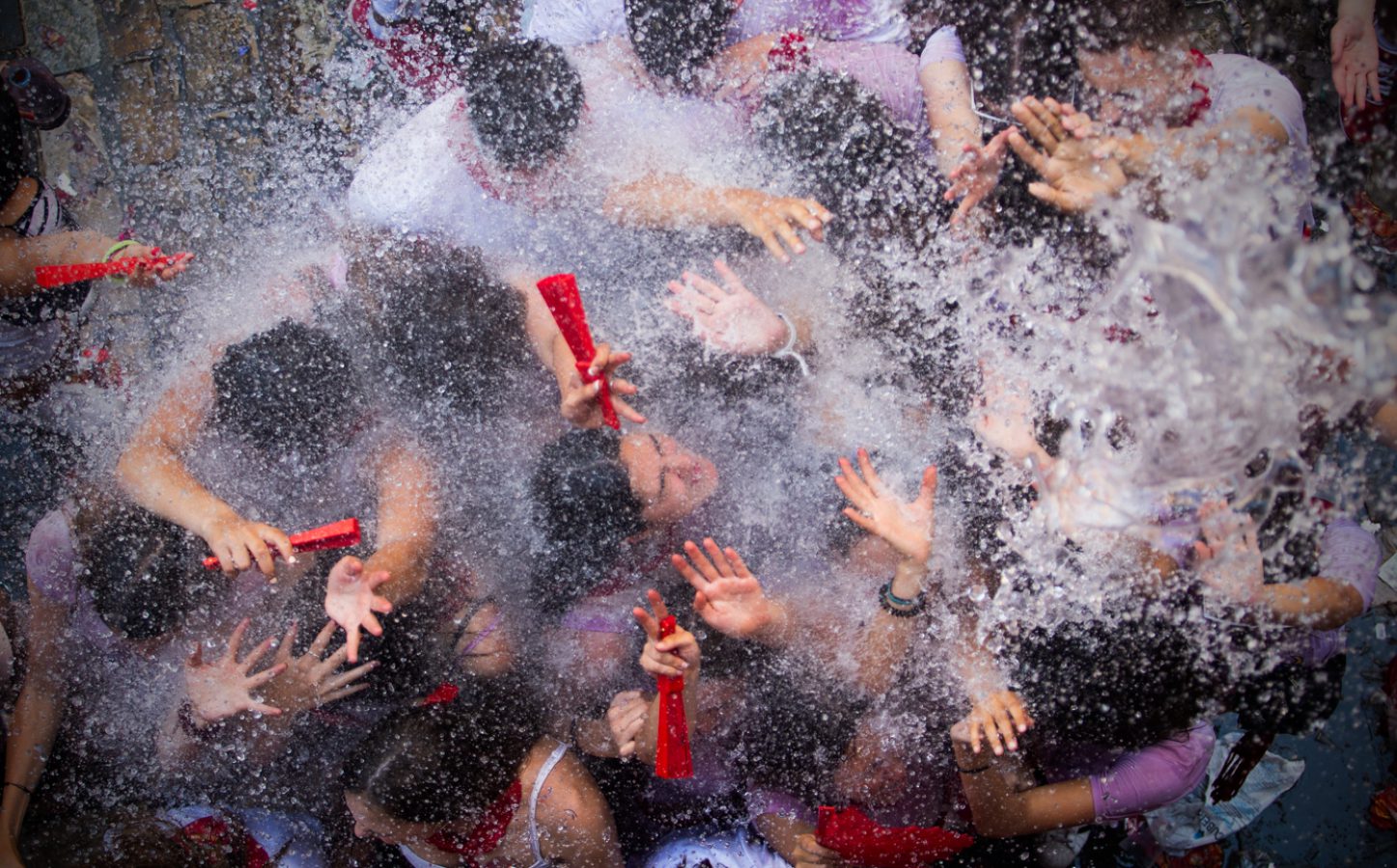 Jóvenes refrescándose con agua lanzada desde los balcones tras el chupinazo.